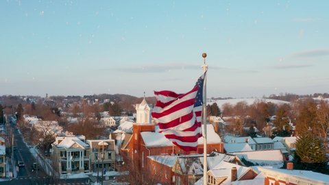 Snow flakes in winter with American flag aerial. Anytown USA during Christmas holiday season. Patriotic theme.