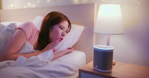 Smart home concept - asian woman use voice control to turn off the light