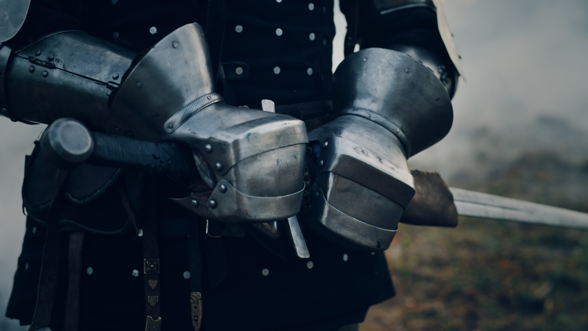 Medieval Knight Wearing Armour and Helmet, Draws Sword from Shearh, Ready to Fight, Kill His Enemy in Battle. Warrior Soldier on Battlefield. War, Invasion, Crusade. Cinematic Historic Reenactment Royalty-Free Stock Footage #1076180768