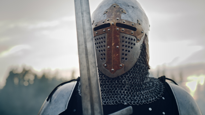 Medieval Knight Wearing Armour and Helmet, Draws Sword from Shearh, Ready to Fight, Kill His Enemy in Battle. Warrior Soldier on Battlefield. War, Invasion, Crusade. Cinematic Historic Reenactment | Shutterstock HD Video #1076180768