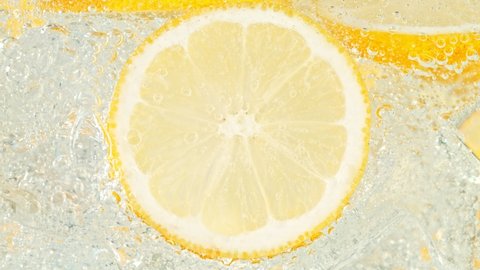 Super Slow Motion Shot of Fizzing Water with Lemon Slices and Ice Cubes in Glass at 1000 fps.