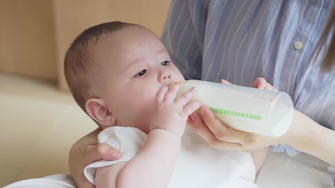 Mother suckling her baby with a feeding bottle.