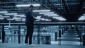 Data Center Engineer Using Laptop Computer. Server Farm Cloud Computing Specialist Facility with African American Male System Administrator Working with Data Protection Network for Cyber Security. - Powered by Shutterstock - Get 15% off with code: PIKWIZARD15