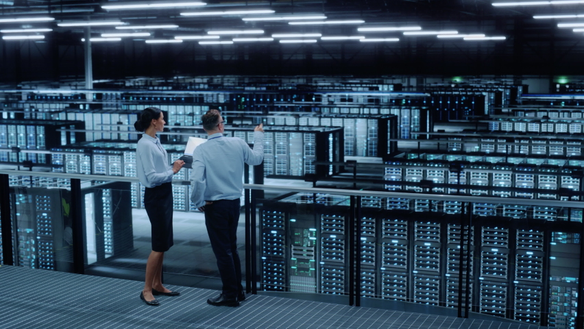 Data Center Female System Administrator and Male IT Specialist Talk, Use Laptop Computer. Information Technology Engineers work on Cyber Security Network Protection in Cloud Computing Server Farm. Royalty-Free Stock Footage #1076186510
