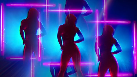 Silhouette of sexy woman dancing on glowing square of led red lamps background. She looks seductively. Sexy outfit . Kaleidoscope effect. Blue smoky studio.