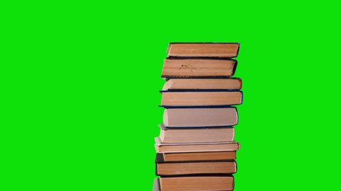Lots of pile of books growing on green chroma key background. Teaching and learning science concept. A stack of books on a wooden table, stop motion, time laps.