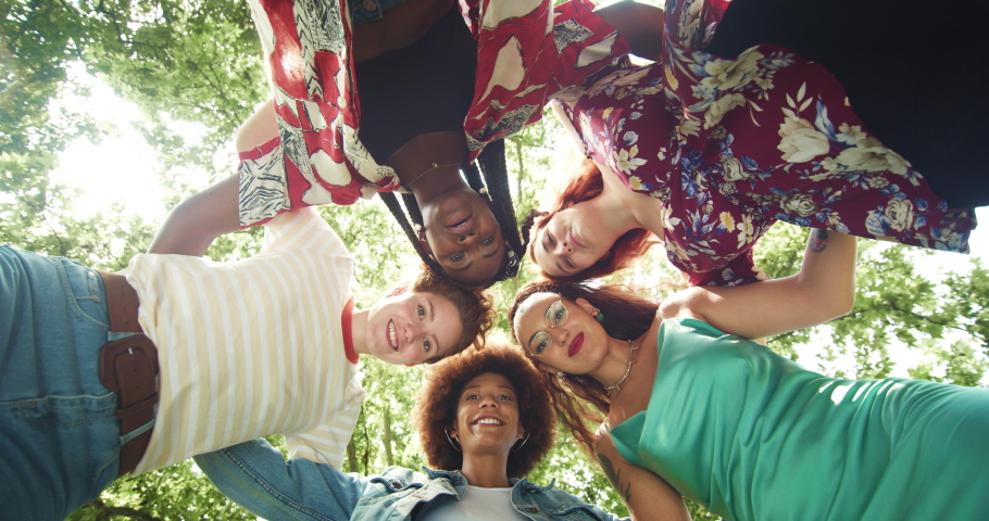 Low Angle: Group of Multiethnic Women Forming a Circle and Turning Around the Camera Outdoors. Young Diverse Female Friends Dancing Around the Camera and Looking at it, Being Playful and Having Fun  Royalty-Free Stock Footage #1076192834