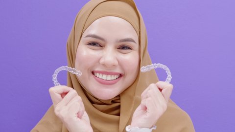 Young muslim woman holding Invisalign braces in studio, dental healthcare and Orthodontic concept.	
