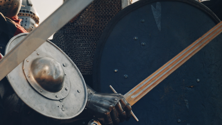 Epic Invading Army of Medieval Knights on Battlefield, Plate Body Armored Soldiers Hit Shields with Swords in Battle Cry. War and Conquest. Historical Reenactment. Cinematic Medium Close-up