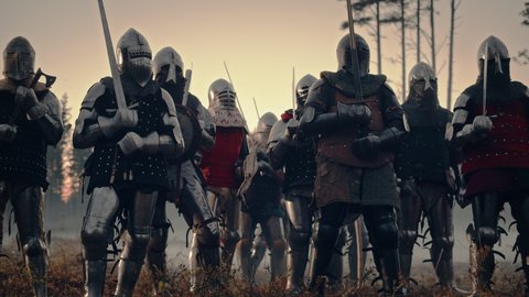 Epic Invading Army of Medieval Knights on Battlefield. Armored Soldiers in Helmets, With Shields and Swords ready for the Battle. War, Conquest, Crusade. Historical Reenactment. Cinematic Wide Shot