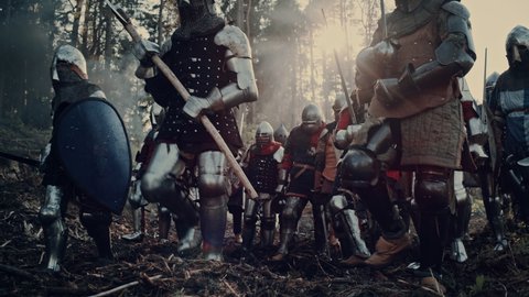 Epic Invading Army of Medieval Soldiers Marching Through Forest. Armored Warriors with Swords Moving to Battlefield. War, Battle, Conquest in Dark Ages. Cinematic Historical Reenactment. Slow Motion