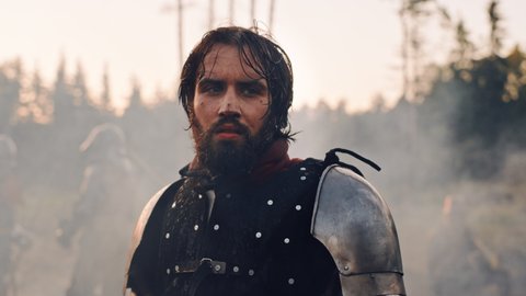 Handsome Medieval Knight King on Battlefield, Looking at Camera. Portrait of Mighty Warrior Soldier Contemplating Victory. War, Invasion, Conquest. Dramatic Scene in Cinematic Historic Reenactment
