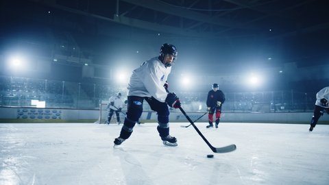 Ice Hockey Rink Arena: Professional Forward Player Masterfully Dribbles, Breaks Defense, Hitting Puck with Stick gives Perfect Pass. Strong Performance Teams Play. Cinematic Slow Motion Wide Shot