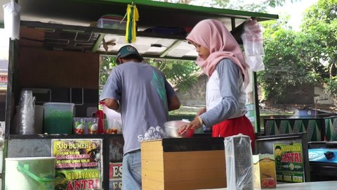 Kediri, East Java, Indonesia - June 25th, 2021 : The seller of es pisang ijo (green banana ice or mix fruit ice). Es pisang ijo contain of banana, coconut milk, ice, and various fruit