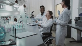 Slowmo tilt up shot of diverse team of male and female scientists in white coats and gloves looking at research results and celebrating by high-fiving each other - Powered by Shutterstock - Get 15% off with code: PIKWIZARD15