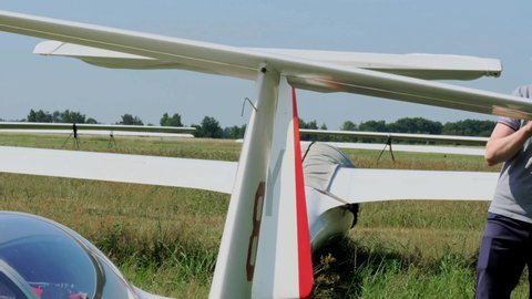Glider pilot getting ready for flight on fixed-wing aircraft from parking airfield. Man sitting in cabin before taking off. Soaring sport club, extreme activity. Buzova, Kyiv, Ukraine - 07.07.2021