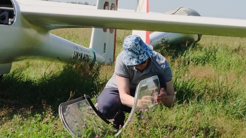 Man prepares and checks gliders parked in the field, ready to fly. Small aviation extreme sport leisure activity. Buzova, Kyiv, Ukraine - 07.07.2021