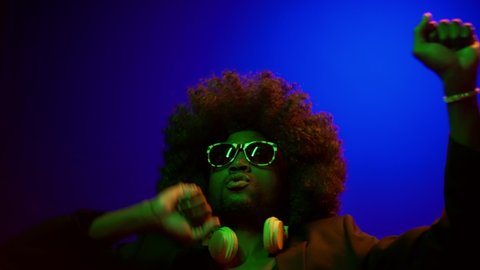Afro American PJ in Afro Wig Dancing in Night Club in Modern Neon Light. Student Resting and Enjoying Music. Handsome Man Listening Djs Mix and Dance. Smooth Hand Movements to Rhythm. High quality 4k