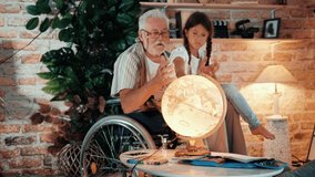 Granddaughter and grandpa with disability looking at a globe and teach geography in living room, education concept. - Powered by Shutterstock - Get 15% off with code: PIKWIZARD15
