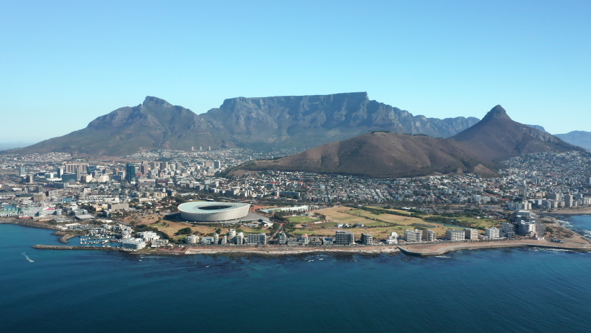 Cape Town Stadium At The Sea Coast In Cape Town, South Africa With Signal Hill And Table Mountain National Park In Background. wide aerial shot