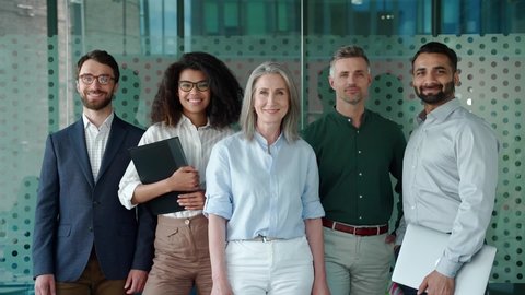 Happy diverse business people office workers team standing in row looking at camera. Multiethnic professional employees executives group posing together for corporate portrait, leadership. Slow motion
