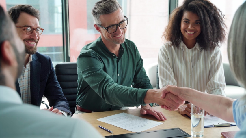 Businessman client signing trust partnership contract at group meeting with lawyers handshaking partner sitting at office table. Ceo putting signature making legal financial agreement at negotiations. Royalty-Free Stock Footage #1076215754