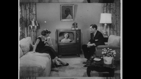 1950s Chicago, IL. Married Couple watching Television in Family Room. Female TV personality performs on the Television Set. 4K Overscan of Vintage Archival 16mm Film Print. 