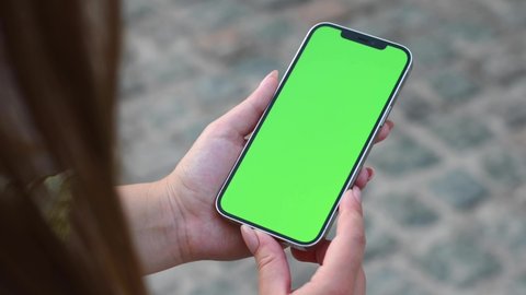 Woman holding a phone in hands with green screen 