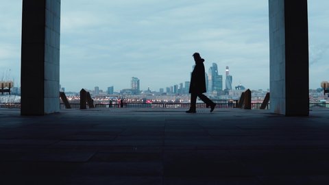 The silhouette of a guy who is walking against the background of a large metropolis. Loneliness in the big city