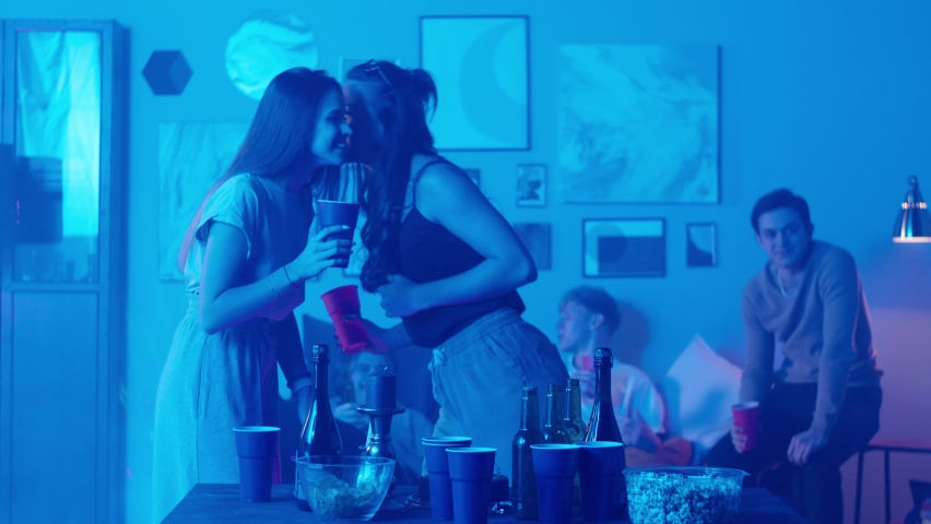 Group of students dancing at home, women gossiping, having party during coronavirus lockdown, dance together in living room at night. Young friends millenials celebrate birthday holiday. | Shutterstock HD Video #1076220710