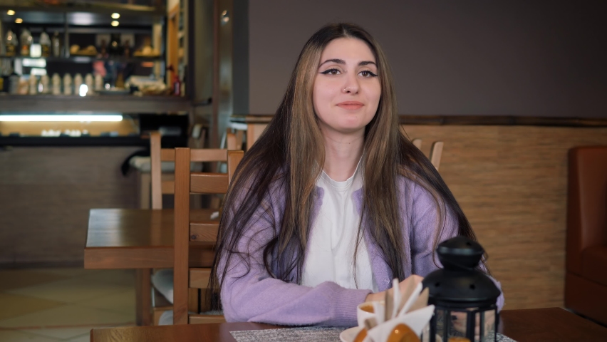 Girl smiles, braces are visible, and brings the cup to her lips.