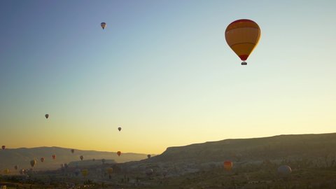 Goreme, Cappadocia, Turkey - May 30, 2021: Ballooning in Kapadokya. Many hot air balloons flying over spectacular breathtaking unusual valleys and rocks in blue sunrise morning sky