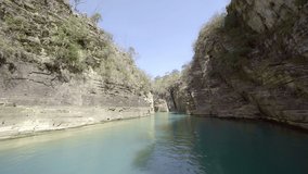 Boat navigating trough canyons of sedimentary rocks, vegetation and green water. Eco tourism destination of Capitolio national park in the region of the Furnas Reservoir in Minas Gerais, Brazil.