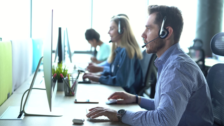 Focused male representative call center agent in wireless headset helping client with complaints using computer in office, corporate operator working in customer support service on helpline telesales Royalty-Free Stock Footage #1076237435
