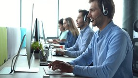 Focused male representative call center agent in wireless headset helping client with complaints using computer in office, corporate operator working in customer support service on helpline telesales
