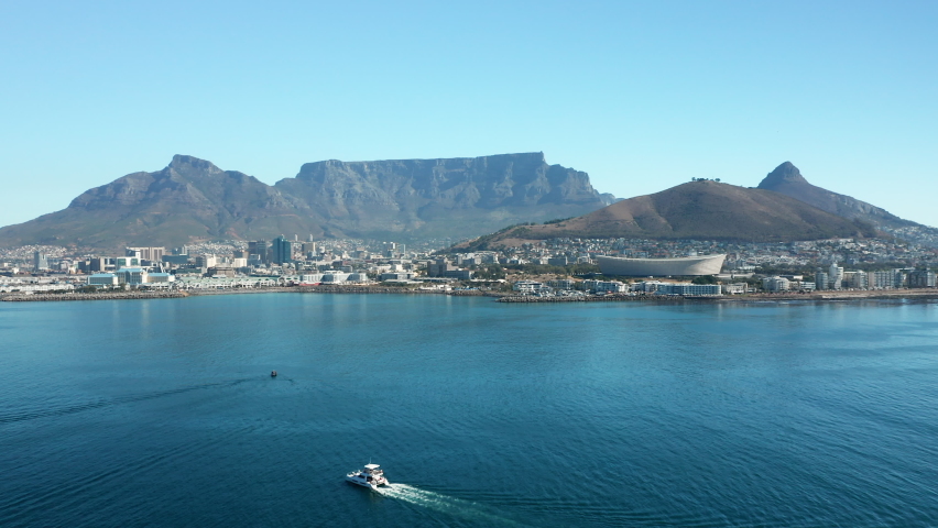 Sailboat Traveling Towards The Seaport Of Cape Town With A View Of The Signal Hill And Table Mountain In South Africa. aerial