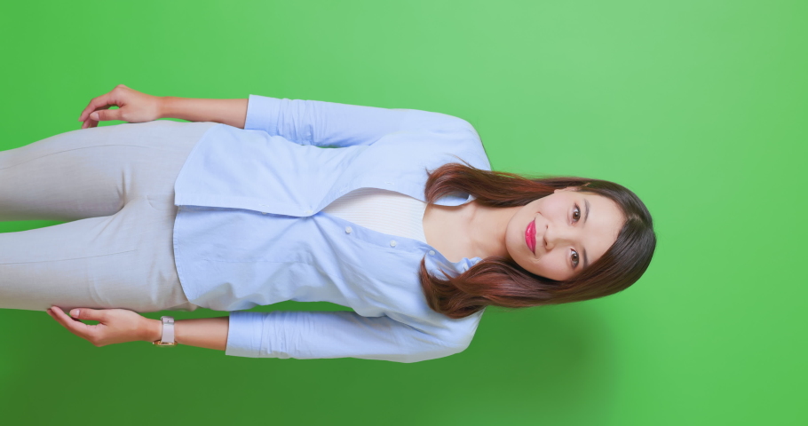 vertical video - asian female confident anchor or businesswoman is standing in front of green background with crossed arms Royalty-Free Stock Footage #1076242340