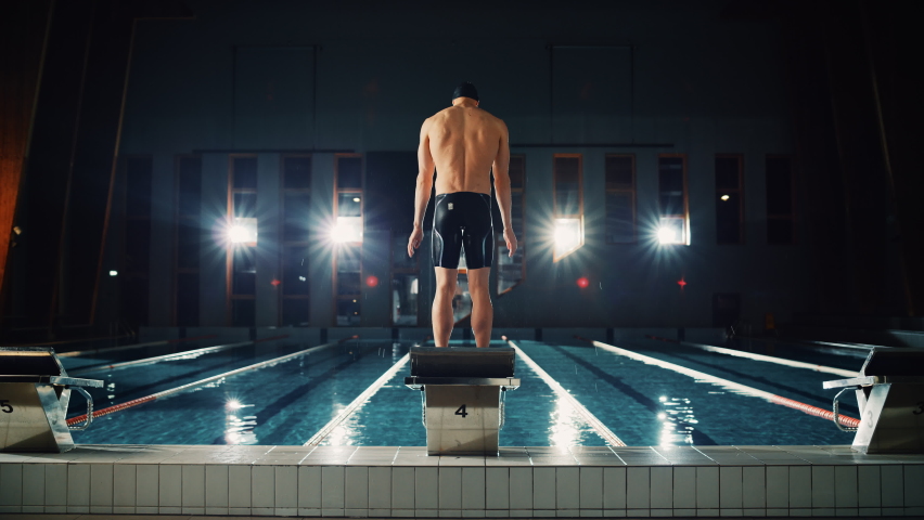 Muscular Male Swimmer Comes to Starting Block to Jump and Dives into Swimming Pool. Professional Man Athlete Ready to Win Championship. Cinematic Light, Slow Motion, Flare Light, Back View Wide Shot | Shutterstock HD Video #1076243840