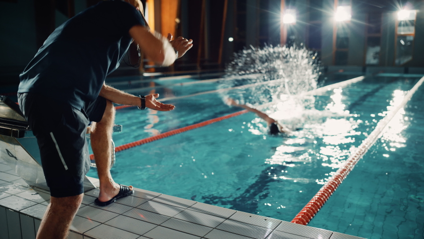 Swimming Pool: Professional Trainer Training Future Champion Swimmer. Experienced Coach Does High-Five with Successful Male Swimmer. Team Ready for World Record and Victory. Cinematic Slow Motion Royalty-Free Stock Footage #1076243882