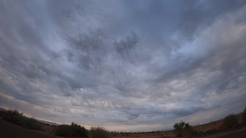 Dark storm clouds produce a rare cloudburst over the arid Mojave Desert basin - static wide angle time lapse