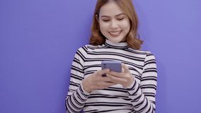 Portrait of young pretty woman is using smart phone over blue background 