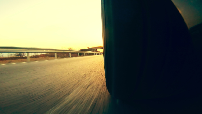 Low angle side view of car driving fast at sunset with motion speed effect .