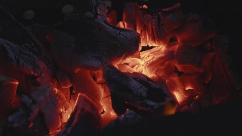 Burning coal in the dark, smoldering coal throwing up red sparks and fire. charcoal for a barbecue. just a good view to relax in front of fireplace. warmth of a fading bonfire. closeup of a campfire