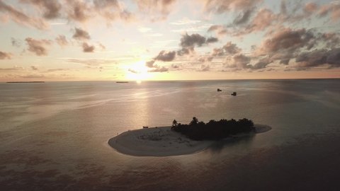 DLOG Flat Island in the sea. Maldives white sand beach tropical islands with drone aerial flying birds eye view with aqua blue sea water and sunny sky during sunset