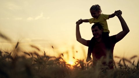 Happy family of farmer. Daughter sits on farmer father neck .Family at sunset in wheat field. Businessman in wheat field with his daughter. Businessman father holding daughter around his neck