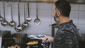 Professional cook is preparing meal in restaurant's kitchen. Slow motion video.