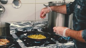 Professional cook is preparing meal in restaurant's kitchen. He is inserting spices in meal during cooking. Slow motion video.
