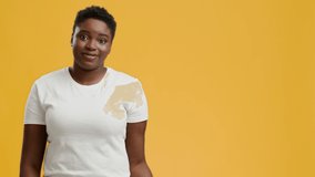 Cheerful Overweight Black Woman Gesturing Showing Copy Space For Advertisement Posing Smiling To Camera Over Yellow Background In Studio. African American Lady Advertising Your Text