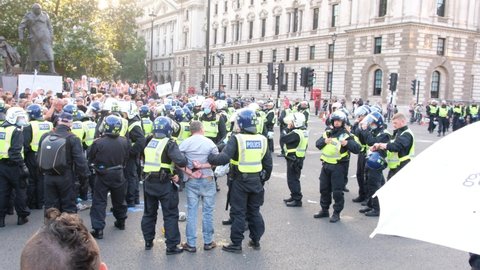 LONDON, UK – July 19, 2021: ‘Freedom Day’ anti-lockdown, anti-vaccination protesters is arrested and handcuffed at Parliament Square, London, England, UK