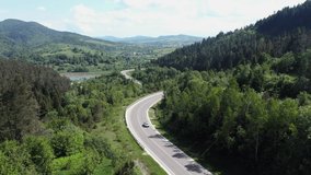 Flight over the summer mountains with mountain road serpentine, river and forest. Ukraine, Carpathian mountains. Footage from drone. UHD 4k video